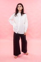 Person wearing a white shirt and dark pants on a pink background
