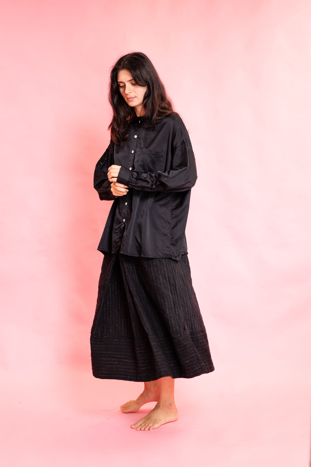 Model wearing a black silk shirt and black wool stripe skirt