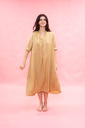 Woman wearing a beige dress against a pink background