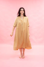 Woman wearing a beige dress against a pink background