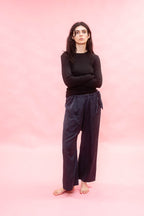Person wearing a black top and dark pants on a pink background