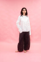 Person wearing a white shirt and dark pants on a pink background