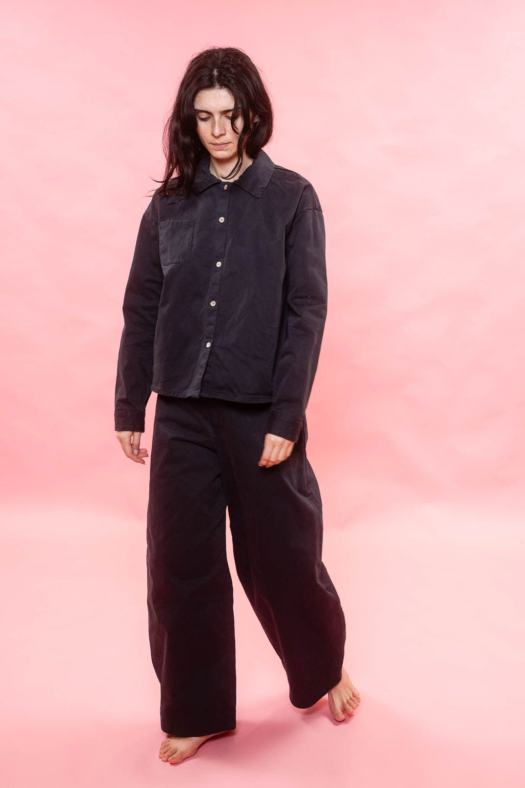 Person wearing a black outfit on a pink background