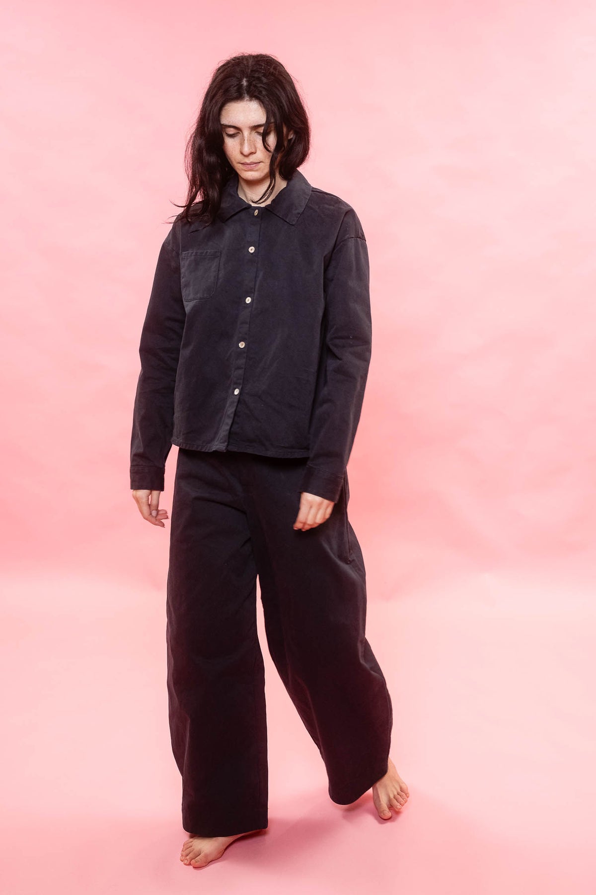 Person wearing a black outfit on a pink background