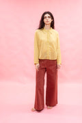 Woman wearing a yellow shirt and red pants on a pink background