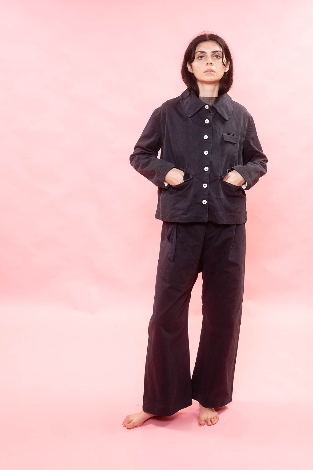 Person wearing a dark outfit on a pink background