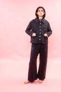 Person wearing a dark outfit on a pink background