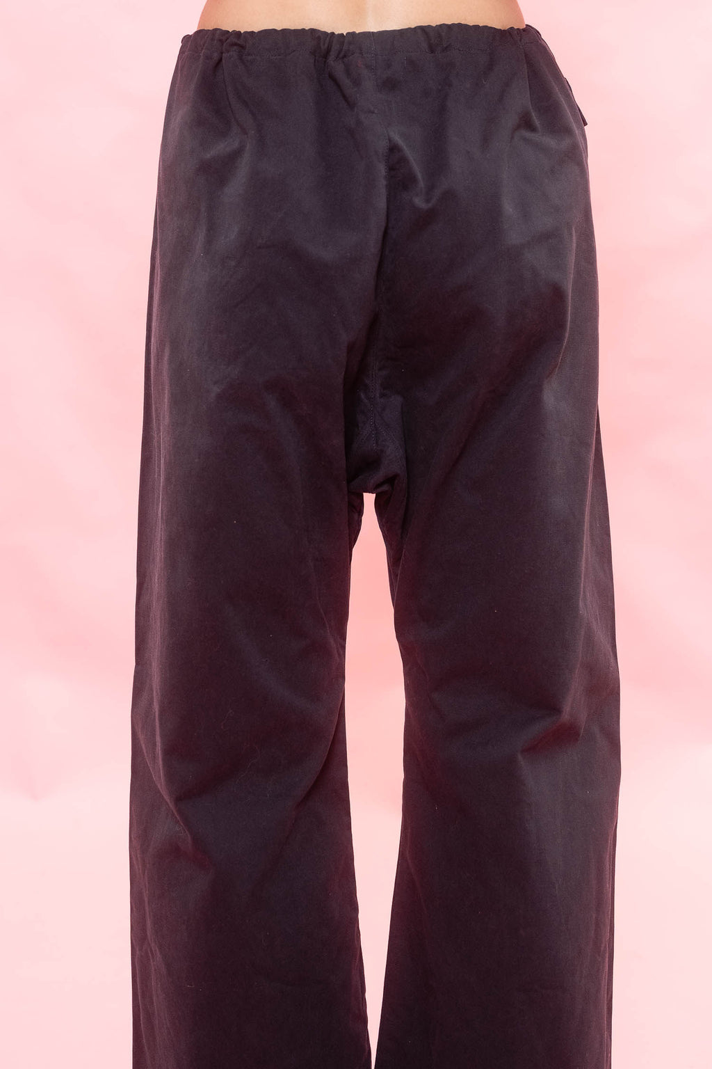 Navy wide-leg pants with a drawstring waist, shown from the back against a pink background.