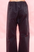 Navy wide-leg pants with a drawstring waist, shown from the back against a pink background.