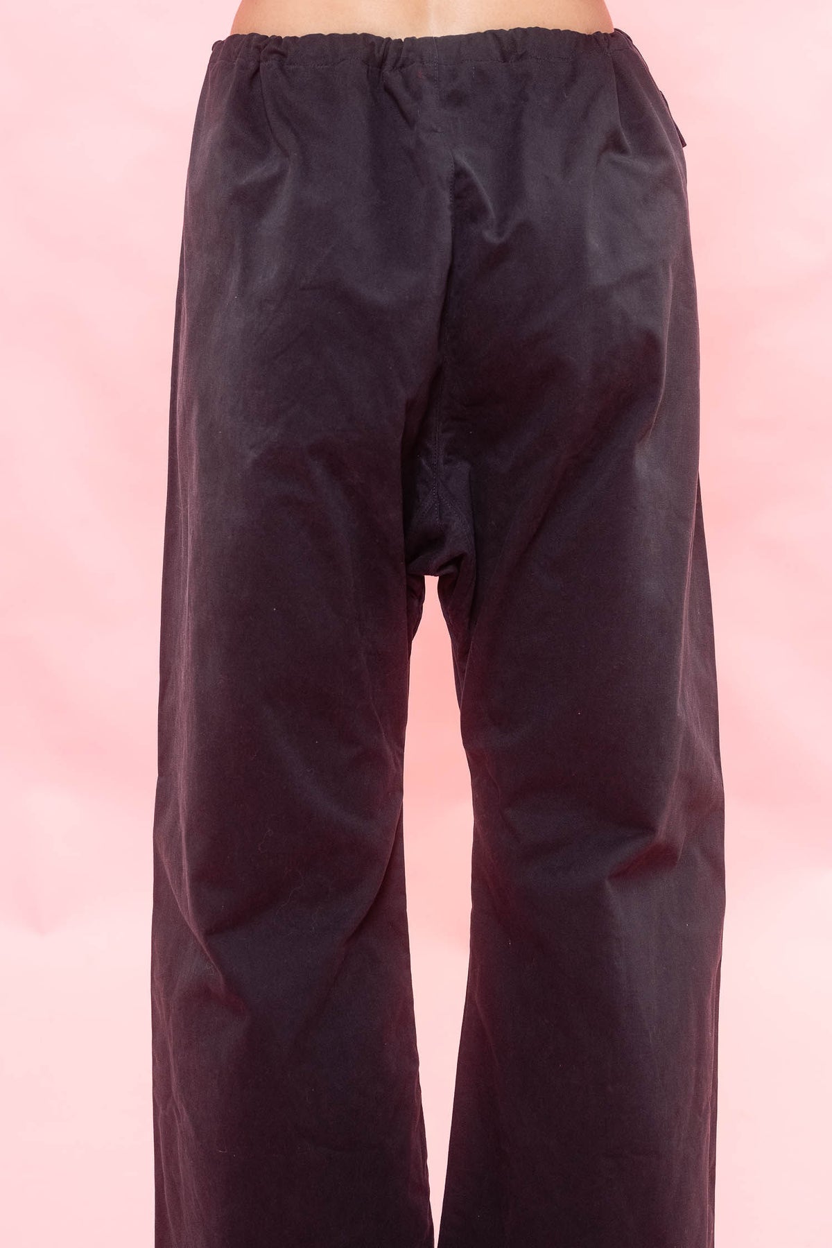 Navy wide-leg pants with a drawstring waist, shown from the back against a pink background.